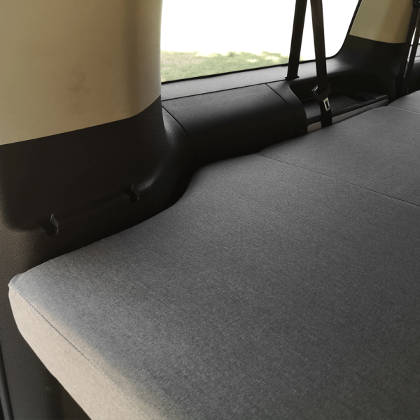 Zoom sur la housse du matelas dans un van PSA, tissu gris clair ajusté à la carrosserie intérieure.
