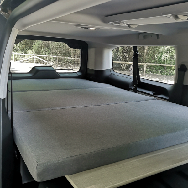 Matelas camping-car gris clair avec découpe adaptée à la forme du coffre, plié en 3 parties.